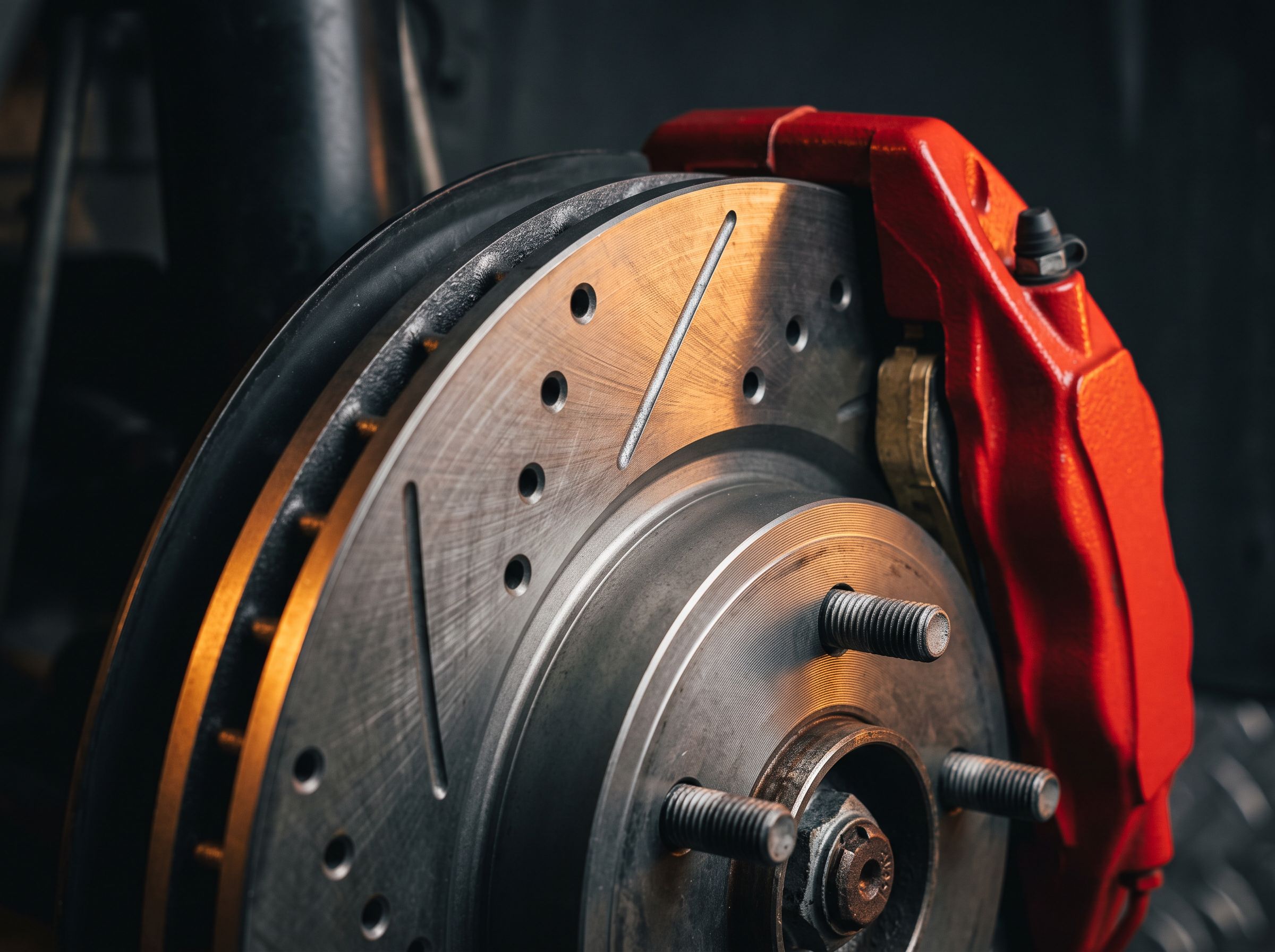 Macro close-up of a drilled and slotted brake rotor with a red caliper